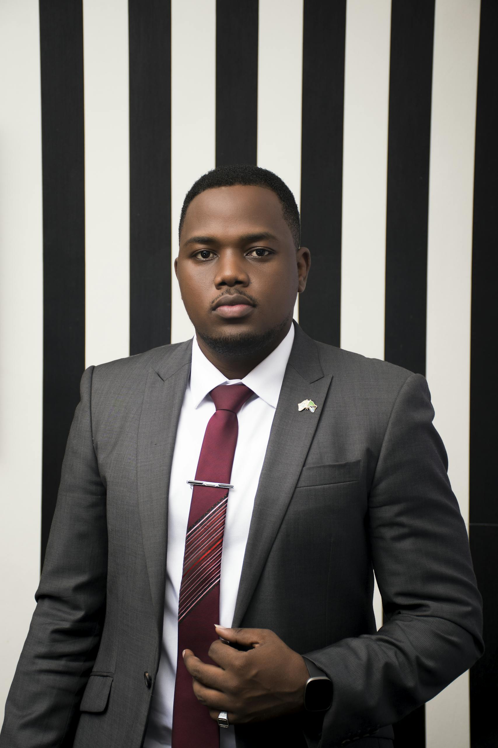 Business portrait of a black man wearing formal attire against a striped background.